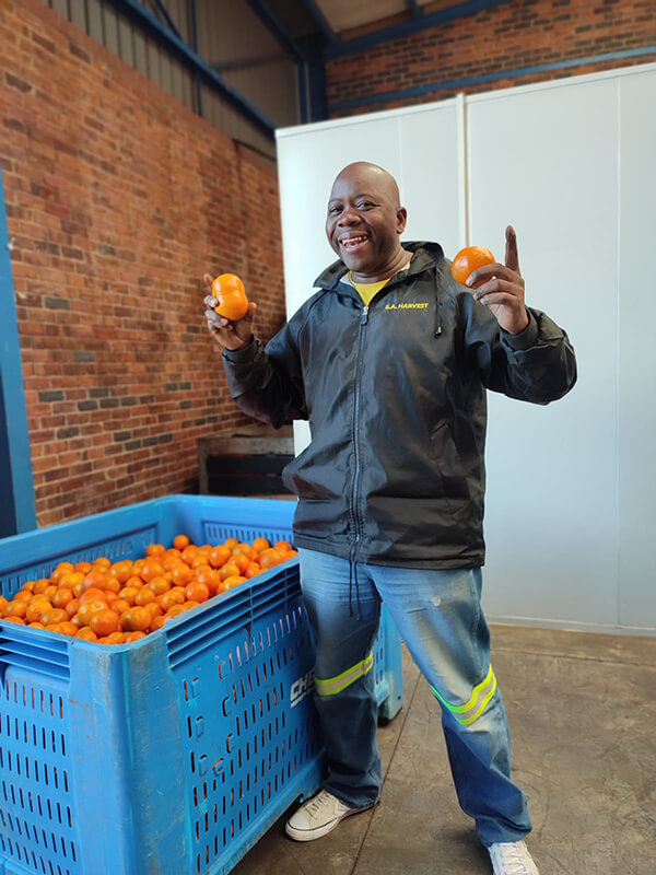 SA_Harvest_team_member_Moses_Mkhize_with_a_delivery_of_mandarins_donated_by_Clemengold_in_CHEF_bins_facilitated_by_OneFarm_Share.jpg