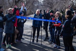 Mina Guli is helped over the finish line of the 100th marathon in her #RunningDry campaign by local New York supporters