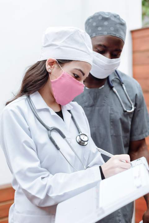 Woman in White Scrub Suit Holding Pink Plastic Cup