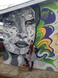 Leleti Khumalo in front of the mural of her, painted by Mathew Pastelos (Pastel Heart)