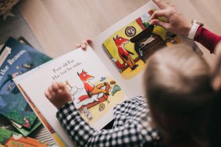 A retired woman shares a moment of magic while reading to the youngster she is childminding.